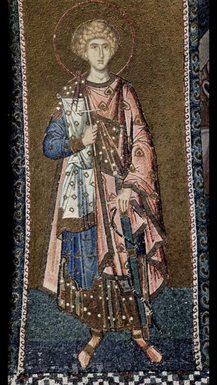 A mosaic showcasing a blond man with a long blue tunic, a smaller white tunic on top of it, and a pink Byzantine style chlamys