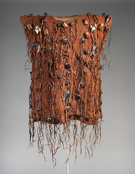 A brown sleeveless tunic covered in tassels and various pieces of stones, bones, and horns