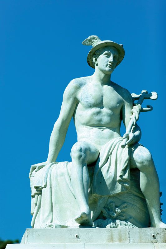 A statue of Hermes. He's sitting down, holding a caduceus across his lap, and wearing a winged petasos.